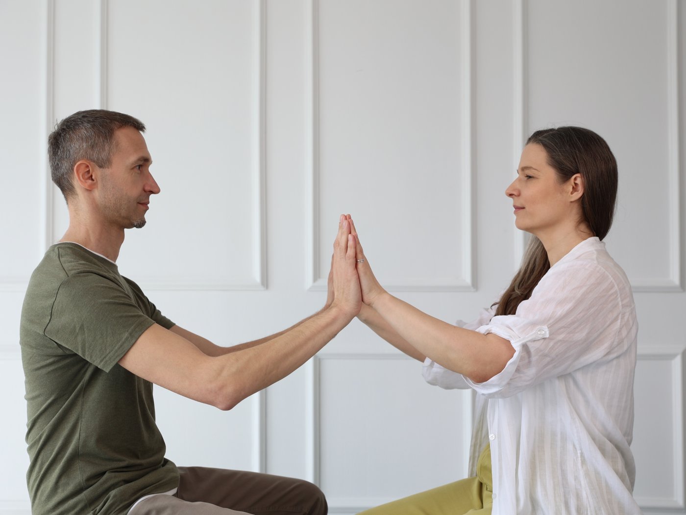 Two seated partners pressing their palms together in a push-hands exercise